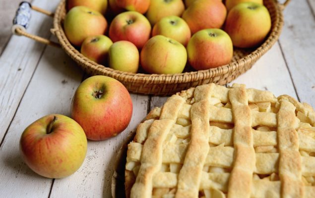 Apples in a basket beside a lattice-top pie